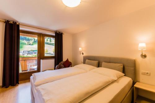 a bedroom with a large bed and a large window at Gasthof Platterwirt in Moso