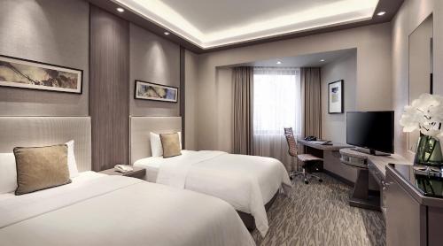 a hotel room with two beds and a desk at M Hotel Singapore City Centre in Singapore