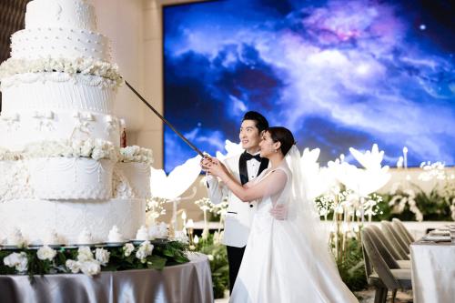 a bride and groom cutting their wedding cake at Grand Mercure Bangkok Atrium in Bangkok