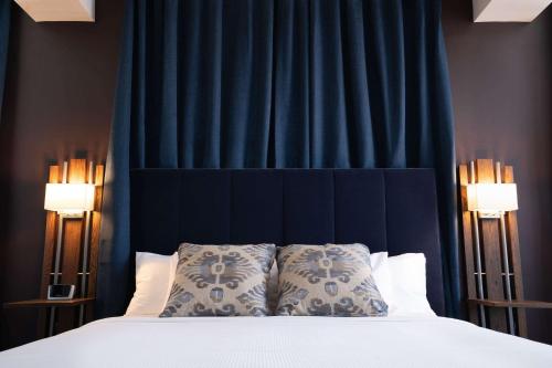 a bedroom with a bed with a blue curtain at The Esquire Hotel Downtown Gastonia, an Ascend Collection Hotel in Gastonia