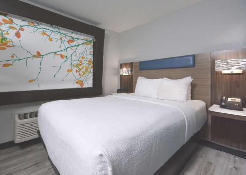 a bedroom with a white bed and a painting on the wall at Brookstone Lodge near Biltmore Village, an Ascend Collection Hotel in Asheville