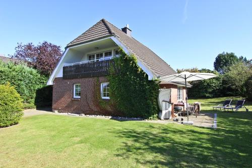 a brick house with a balcony and an umbrella at Ferienhaus Ostseerausch in Scharbeutz