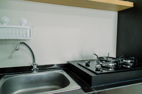 a kitchen sink with two pots and pans on a stove at Simply and Comfort Living 2BR at Transpark Bintaro Apartment By Travelio in Tangerang