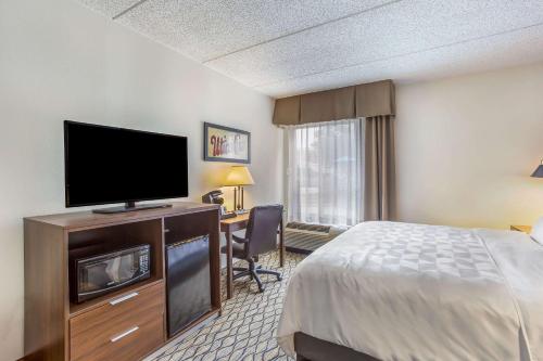 a hotel room with a bed and a flat screen tv at Burrstone Inn, an Ascend Collection Hotel in Utica