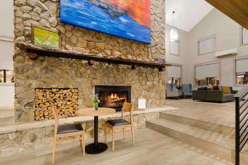 a stone fireplace in a lobby with a table and chairs at Graystone Lodge, an Ascend Collection Hotel in Boone