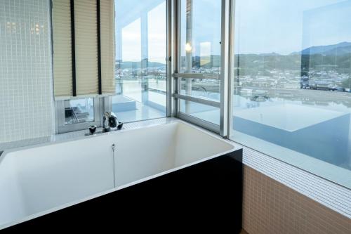 a white bath tub in a bathroom with a large window at Hita Onsen Kizantei Hotel in Hita