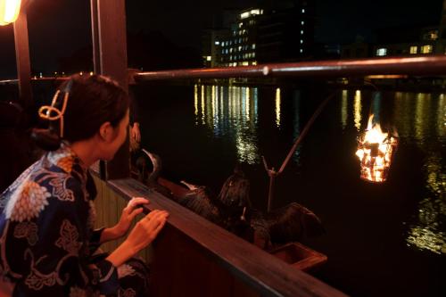 a woman sitting on a railing looking at birds at night at Hita Onsen Kizantei Hotel in Hita