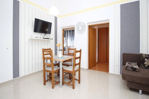a living room with a table and chairs and a tv at Apartments Zarok Beach Holiday in Baška