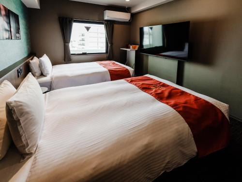 a hotel room with two beds and a television at Music Hotel Koza by Coldio Premium in Okinawa City