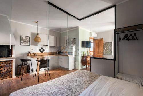 a bedroom with a white bed and a kitchen at SopraBosco Calcata Art & Design Apartment in Calcata