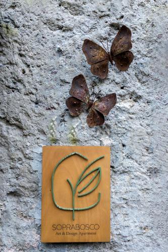 two butterflies sitting on a wall with a sign at SopraBosco Calcata Art & Design Apartment in Calcata