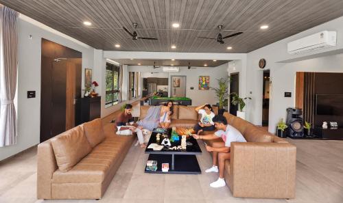 a group of people sitting on a couch in a living room at SaffronStays Earl Grey in Khandala