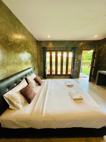 a bedroom with a large bed with white sheets and pillows at The Loft Baannaisuan in Chiang Rai