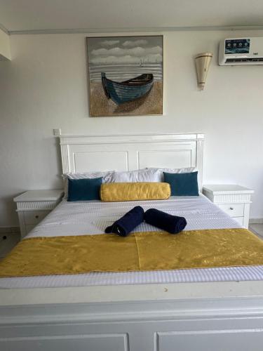 a white bed with a yellow blanket and a boat on it at Sealaview in Ukunda