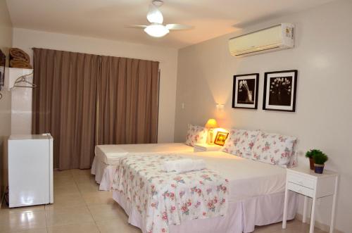 a bedroom with two beds and a ceiling fan at Hotel São José in São Fidélis