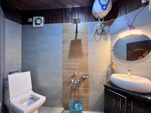 a bathroom with a sink and a toilet and a mirror at Traditional Hotel & Restaurant !! Kurseong !! Best Hotel in Kurseong in Darjeeling
