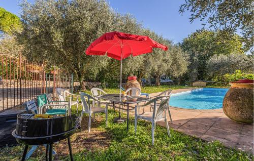 un tavolo con ombrellone e sedie rossi accanto a una piscina di Cozy Home In Peymeinade a Peymeinade