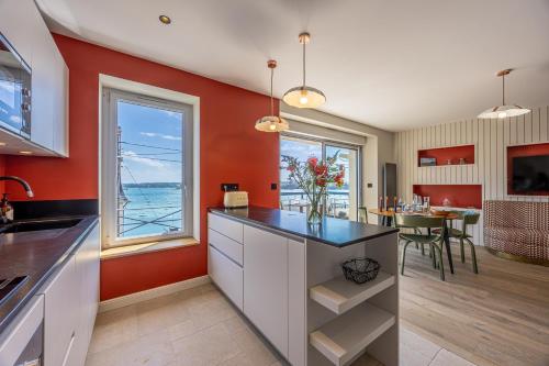 une cuisine aux murs rouges et une salle à manger avec une table dans l'établissement Osiris - Magnifique appt vue mer avec rooftop, à Dinard