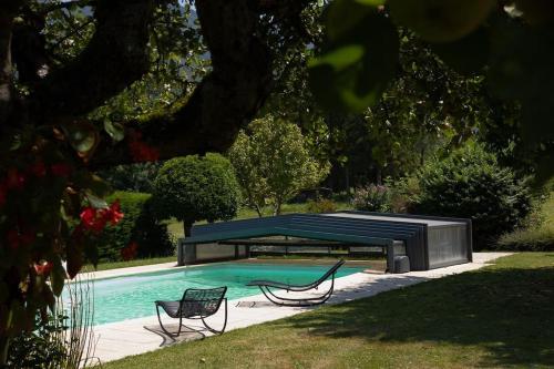 - une piscine avec 2 chaises et un banc à côté dans l'établissement Maison de famille entre lacs et montagnes, à Cusy