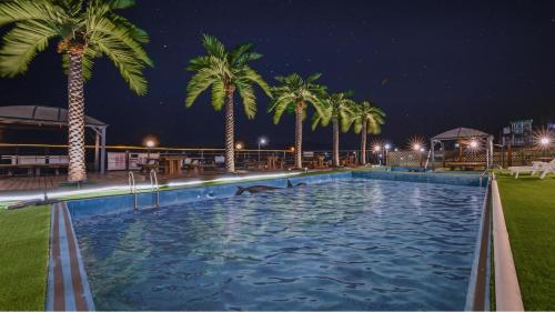 a large swimming pool with palm trees at night at Gyeongju Neulsiwon Pension in Gyeongju