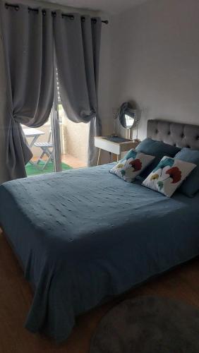 une chambre avec un lit avec des draps bleus et une fenêtre dans l'établissement cosy pres de la cepiere, à Toulouse