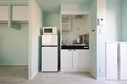 a kitchen with a white refrigerator and a microwave at スカイフィール大久保 in Tokyo