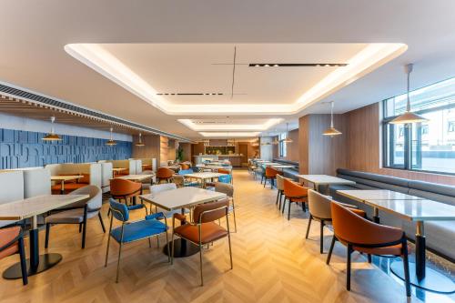 a dining room with tables and chairs and windows at Holiday Inn Express Luoyang Longmen by IHG in Luoyang