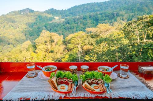 ein Tisch mit Tellern mit Essen und Gläsern Wasser in der Unterkunft Happy camp phuchifa แฮปปี้แคมป์ ภูชี้ฟ้า in Ban Huai Han