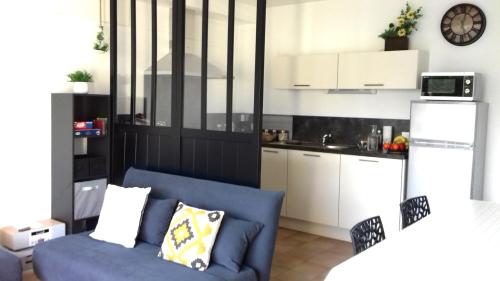 un salon avec un canapé bleu et une cuisine dans l'établissement Maison 2 pièces 4 personnes proche de l'océan - GAELIG, à Sarzeau