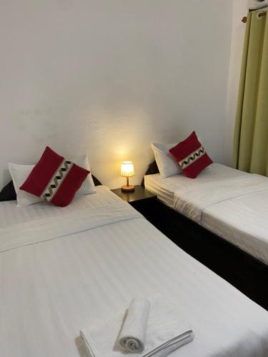two beds with red and white pillows in a room at PHAI GUESTHOUSE in Luang Prabang