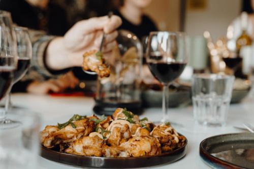a person eating food on a table with glasses of wine at Daft Hotel in Malmedy