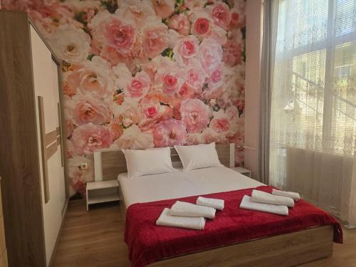 a bedroom with a floral wall with towels on a bed at Roses in Sofia