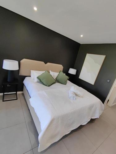 a bedroom with a large white bed with green pillows at Luxury Apartment in Pebble Beach Umhlanga in Umhlanga