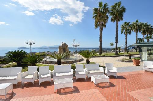 a patio with white chairs and palm trees at Gli Dei in Pozzuoli