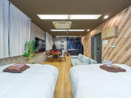 a room with two beds and a living room at Shimbashi Hotel Sho in Tokyo