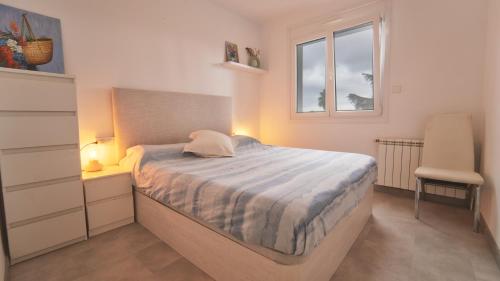 a bedroom with a bed and a window and a chair at SeaHomes Vacations - Villa Serenity Cala Canyelles in Lloret de Mar