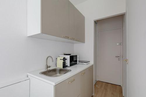 une cuisine blanche avec un évier et un micro-ondes dans l'établissement Bluestay 806 - Superb studio, à Paris