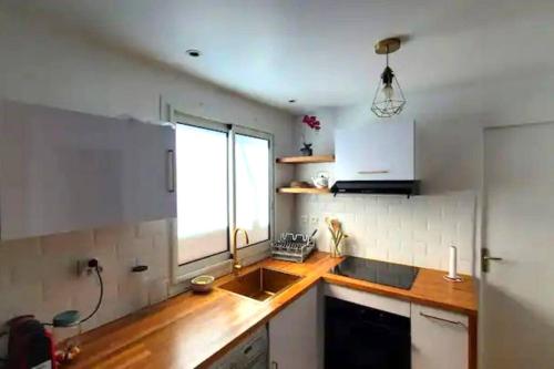a kitchen with a sink and a window at Pépite citadine à St Pierre in Saint-Pierre