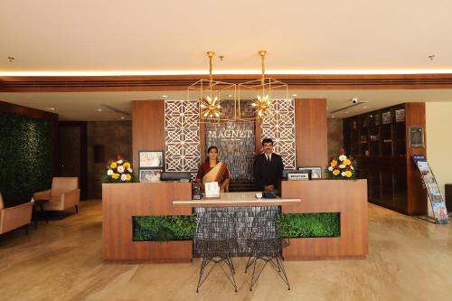 a couple standing at a counter in a hotel lobby at Magnet Hotel in Kannur