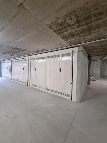 a row of white lockers in a parking garage at The Nest - TRILO - WIFI - Box - Cortile - Magnolta in Aprica