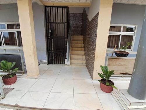 a front door of a house with two potted plants at Appartement New Stading YAOUNDE - MIMBOMAN MAETURE in Yaoundé