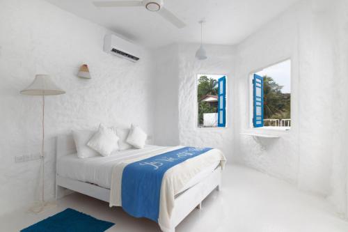 a white bedroom with a bed and a window at Talalla Blue Beach Villa in Matara