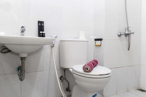 a white bathroom with a toilet and a sink at New and Cozy Studio at Patraland Urbano Apartment By Travelio in Bekasi
