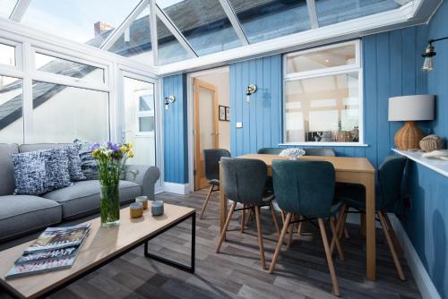 a living room with blue walls and a table and chairs at Harbour Heights by Coast & Country Stays in Seahouses