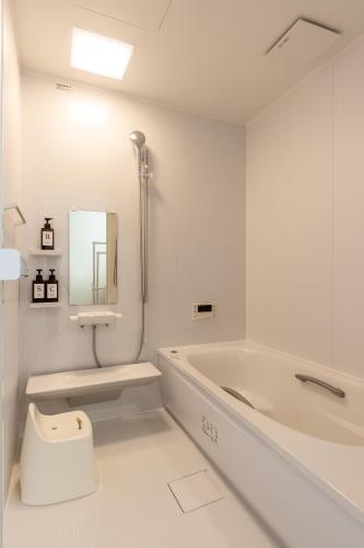 a bathroom with a tub and a toilet and a sink at Snow House LANKA in Furano