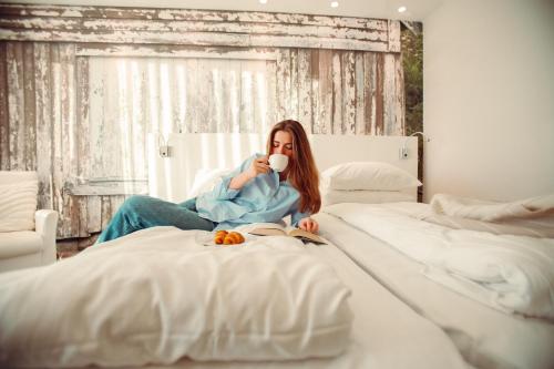 a woman sitting on a bed drinking a cup of coffee at Panorama Hotell & Resort in Steinsland