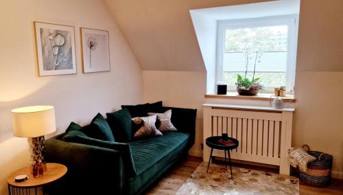 a living room with a green couch and a window at Stilvolle Maisonette Wohnung in Karlsruhe