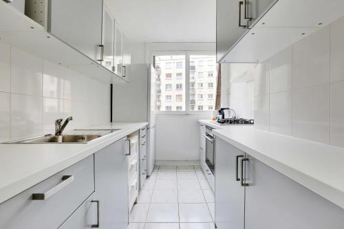 une cuisine blanche avec des armoires blanches et un évier dans l'établissement Charming apartment - 2BR-6P - Paris Expo, à Paris