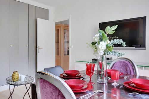 une table à manger avec des plats rouges et une télévision dans l'établissement Charming apartment - 2BR-6P - Paris Expo, à Paris
