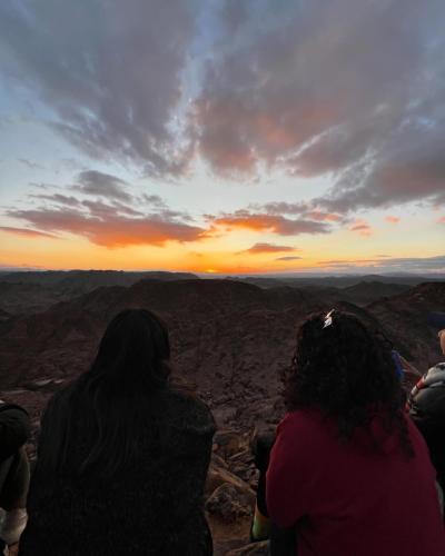 a group of people sitting on the edge of a mountain watching the sunset at Sukoon Nuweibaa in Nuweiba